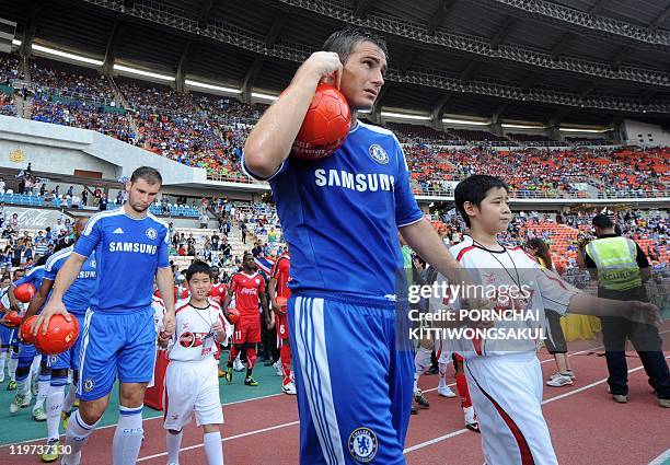 English Premier League team Chelsea player Frank Lampard walks with Thai child ahead of a football friendly match at Rajamangala stadium in Bangkok...