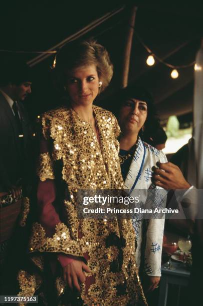 Diana, Princess of Wales receives the gift of a gold embroidered gown during a visit to the museum in Kuwait City, Kuwait, March 1989.