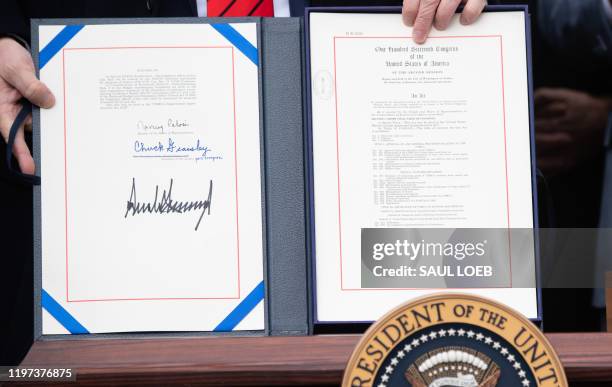President Donald Trump holds up the signed United States - Mexico -Canada Trade Agreement, known as USMCA, during a ceremony on the South Lawn of the...