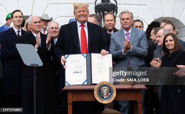 President Donald Trump holds up the signed United States - Mexico -Canada Trade Agreement, known as USMCA, during a ceremony on the South Lawn of the...