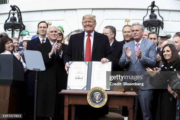 President Donald Trump displays the signed U.S.-Mexico-Canada Agreement on the South Lawn of the White House in Washington, D.C., U.S., on Wednesday,...