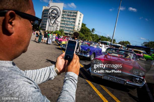 Tourists take pictures near American cars in Plaza de la Revolucion in Vedado, Cuba, on January 17, 2020. The city attracts milions of tourists...