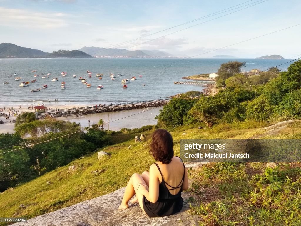 Girl sitting on a rock looking at the sea