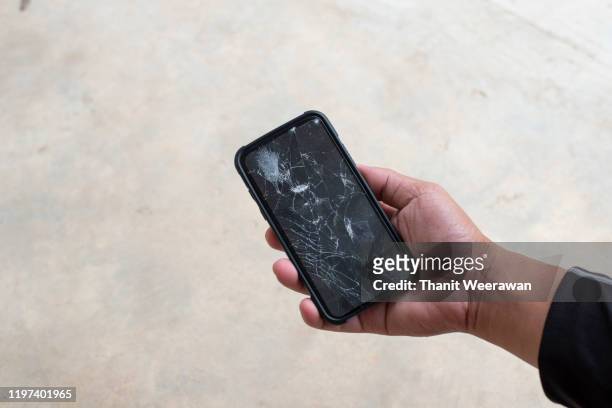 the hand on the phone with the screen broken - broken phone stock-fotos und bilder