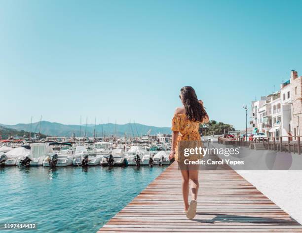 rear view young female walking on pier in catalonia,spain - pasear en coche sin destino fotografías e imágenes de stock