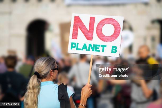 rear view woman with sign at climate change demonstration - climate change protest stock pictures, royalty-free photos & images