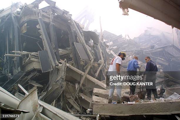 Rescue workers search through the rubble of the twin towers at the World Trade Center in lower Manhattan 11 September in New York after two planes...