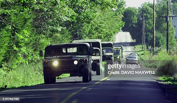 Military vehicles travel along the road 11 September 2001 leading to the crash site of United Airlines Flight 93 in Shanksville, Pennsylvania. The...