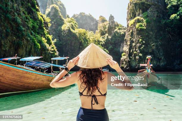 young woman on a beautiful beach in thailand with longtail boats, phi phi island - longtail boat stock pictures, royalty-free photos & images