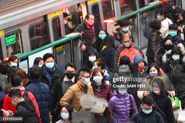 Mask-clad commuters get off a train at a Mass Rapid Transit stop in Taipei following the Lunar New Year holidays on January 30, 2020. - Taiwan has...