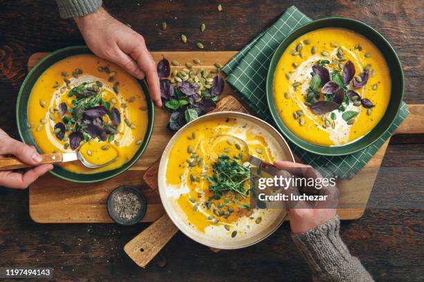 männer essen vegan cremig geröstete kürbissuppe - eating table stock-fotos und bilder