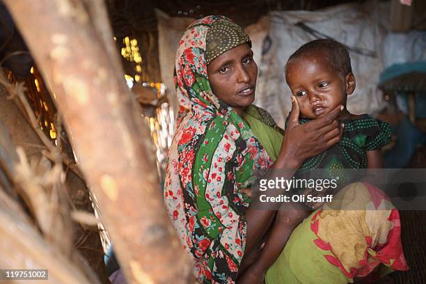 Somali refugee Arfon Mohummd sits with her ill daughter Farhiya Abdi in their makeshift hut on the edge of the Hagadera refugee camp, which makes up...
