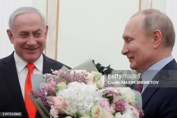 Russian President Vladimir Putin holds flowers next to Israeli Prime Minister Benjamin Netanyahu as they meet at the Kremlin in Moscow on January 30,...