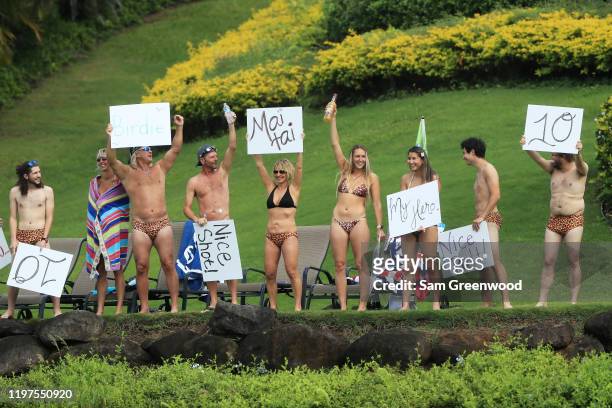 Fans hold up signs from a course side property during the third round of the Sentry Tournament Of Champions at the Kapalua Plantation Course on...
