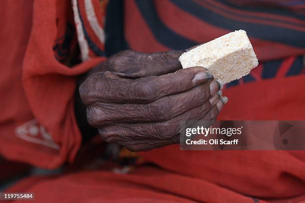 An elderly Somali refugee woman holds a high-energy biscuit ration at the entrance to the registration area of the Ifo refugee camp which makes up...