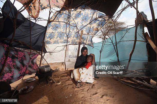 Somali refugee mother and child sit in their makeshift hut on the edge of the Hagadera refugee camp which makes up part of the giant Dadaab refugee...