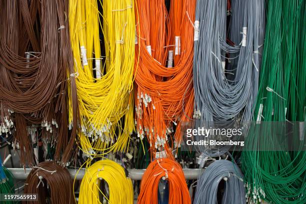Coloured electrical wiring hangs ready for installation to vehicles on the production line at the Kamaz PJSC plant in Naberezhnye Chelny, Russia, on...