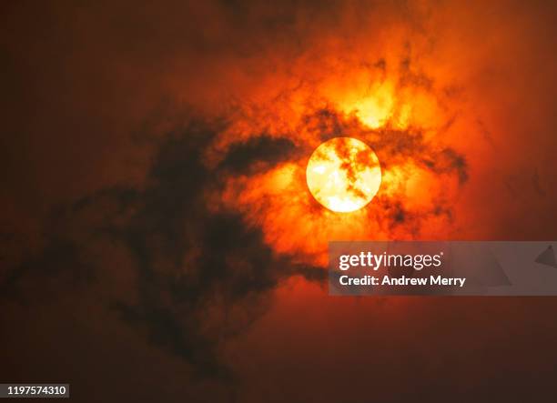 sun through dark smoke clouds from bush fire with red glow, climate change in australia - miraggio foto e immagini stock