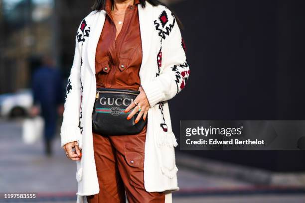 Guest wears a white wool jacket with printed patterns, a brown leather jumpsuit, a Gucci belt bag, during London Fashion Week Men's January 2020 on...