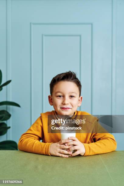 6-7 years old cute child drinking milk on table. he knows that he needs to drink milk for healthy bones. he loves milk. - boys only caucasian ethnicity 6 7 years stock pictures, royalty-free photos & images