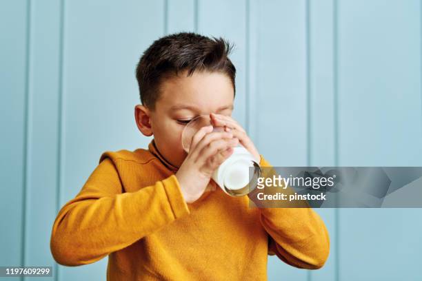 6-7 years old cute child drinking milk on table. he knows that he needs to drink milk for healthy bones. he loves milk. - boy drinking milk stock pictures, royalty-free photos & images