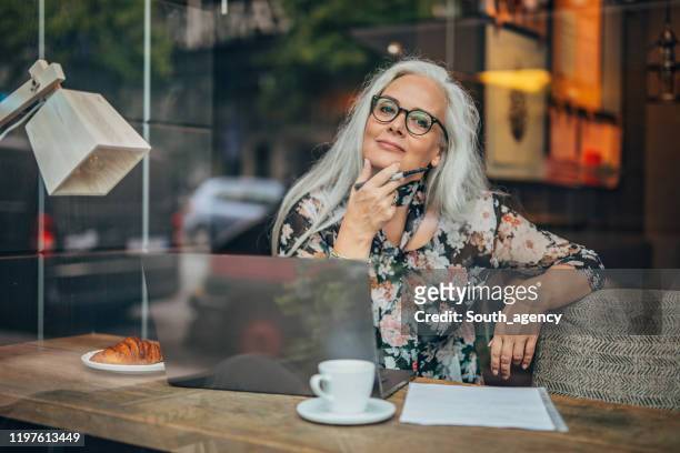 old business woman sitting in cafe alone - author stock pictures, royalty-free photos & images