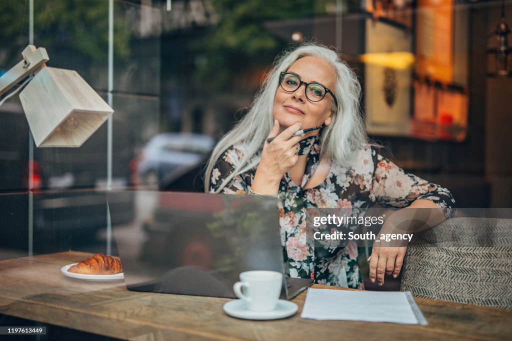 Gamla affärskvinna sitter i Café ensam