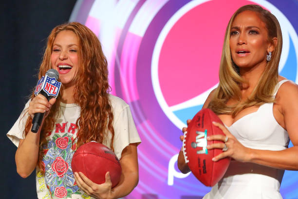 Shakira and Jennifer Lopez get ready to throw footballs during the Pepsi Super Bowl LIV Halftime show press conference on January 30, 2020 at the...