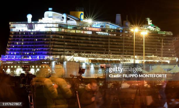 This photograph taken on slow shutter speed shows journalists speaking as they stand in front of the Costa Smeralda cruise ship docked in the...