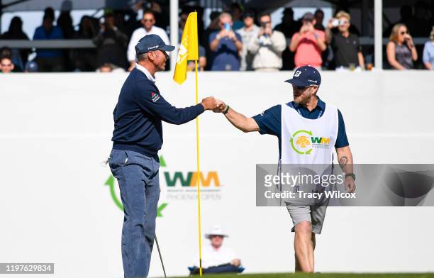 Matt Kuchar fist bumps with his caddie John Wood after he makes birdie at the 16th hole during the first round of the Waste Management Phoenix Open...