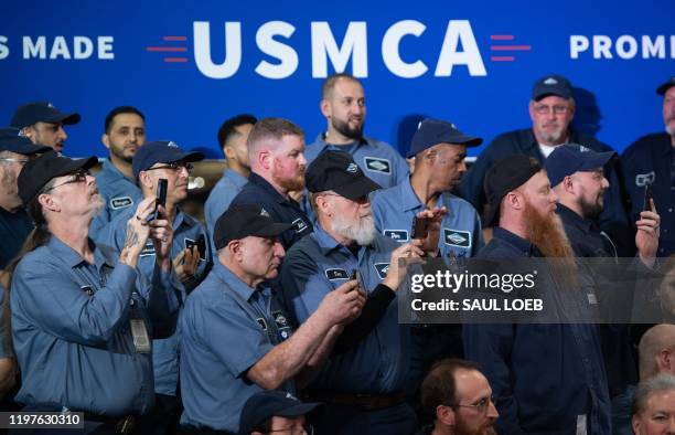 Factory workers watch as US President Donald Trump arrives to speak about the United States - Mexico - Canada agreement, known as USMCA, during a...
