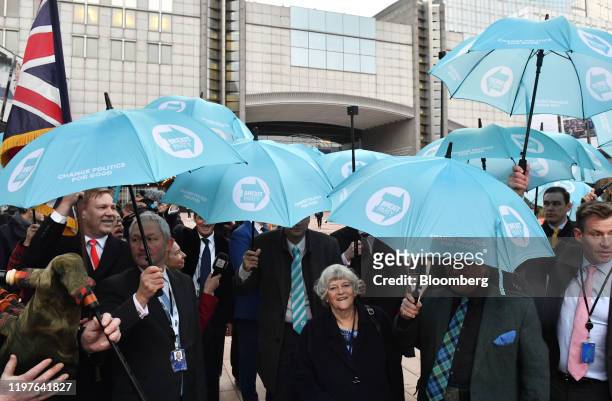 Ann Widdecombe, lawmaker for the Brexit Party, center, stands under umbrellas as she and fellow Members of European Parliament leave the European...