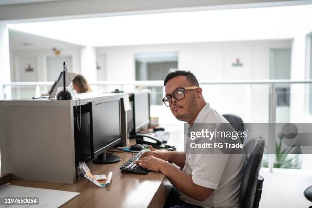 portrait of special needs boy secretary working at hospital reception - developmental disability stock pictures, royalty-free photos & images