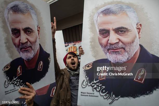 People hold posters showing the portrait of Iranian Revolutionary Guard Major General Qassem Soleimani and chant slogans during a protest outside the...