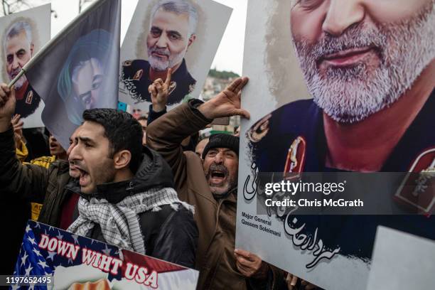 People hold posters showing the portrait of Iranian Revolutionary Guard Major General Qassem Soleimani and chant slogans during a protest outside the...