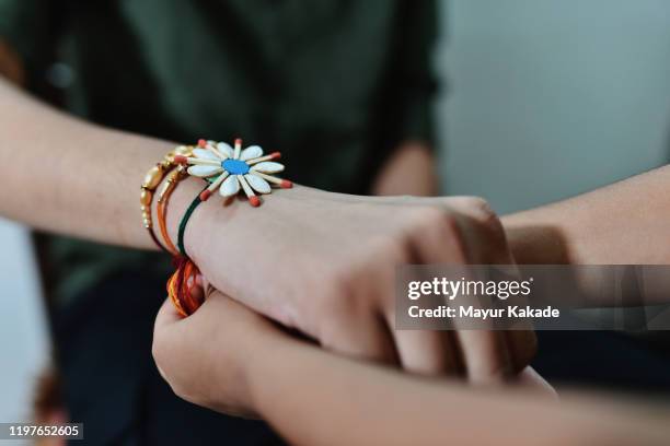 closeup of hands of sister tying rakhi on brothers hands - raksha bandhan fotografías e imágenes de stock