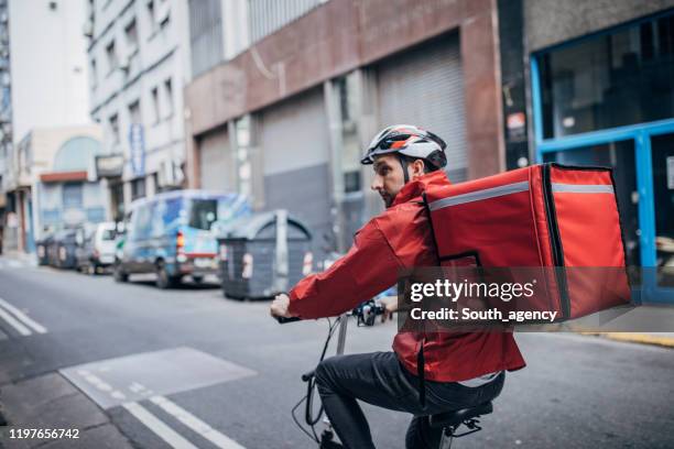 delivery man on bicycle in city - cycling helmet stock pictures, royalty-free photos & images