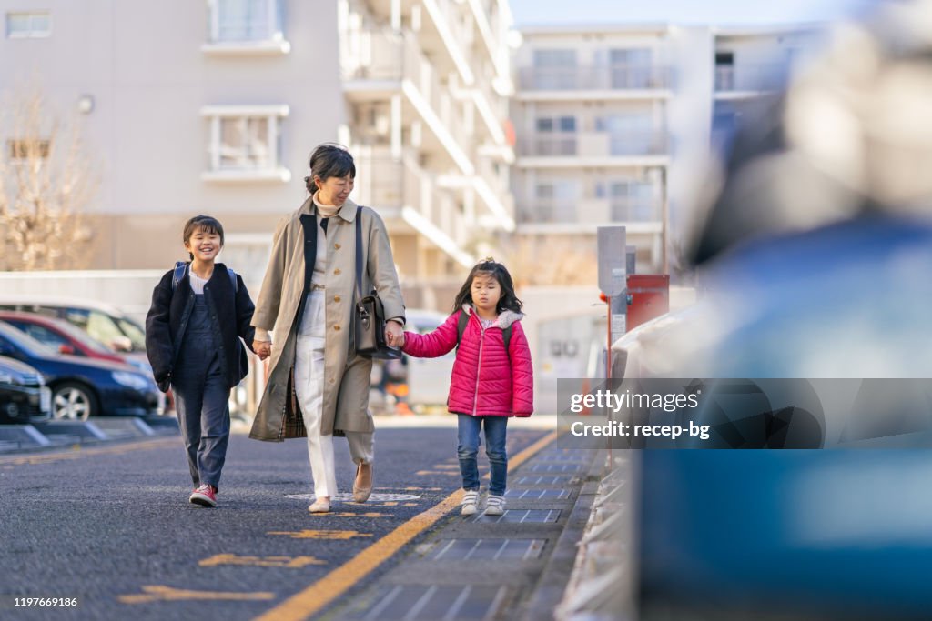 Working mother and sisters walking to car
