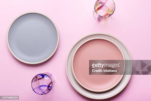 empty plates and drinking glasses on pink background - piatto descrizione generale foto e immagini stock
