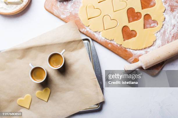 making valentines day cookies, overheard view of two espresso coffee cups and holiday baking - backpapier stock-fotos und bilder