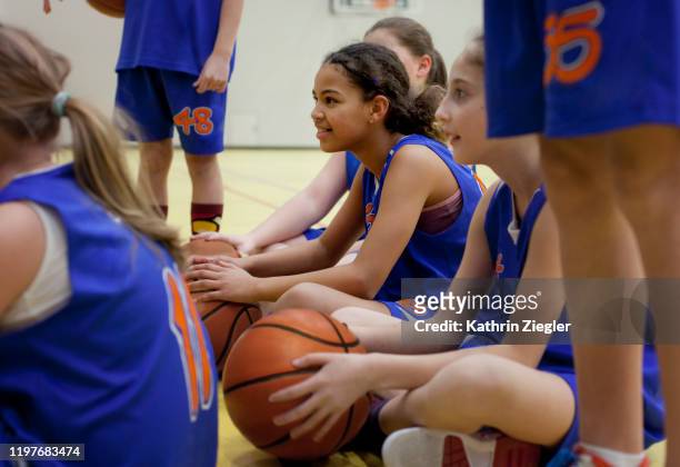 girls' basketball team sitting together before training - kids playing basketball stockfoto's en -beelden