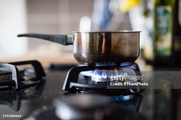 gas flame of gas stove burning under metal saucepan - blue gas flame stock-fotos und bilder