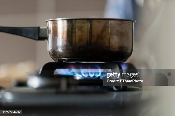 gas flame of gas stove burning under metal saucepan - dirty pan stock pictures, royalty-free photos & images