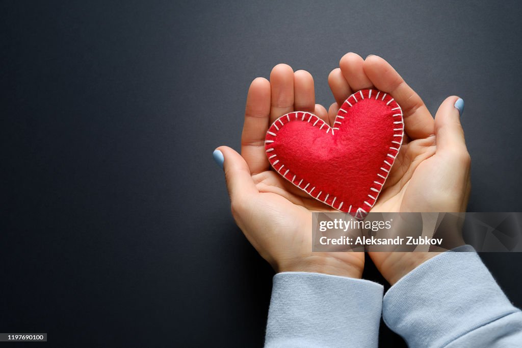The Girl Is Holding A Red Handmade Heart On A Black Background. Banner.