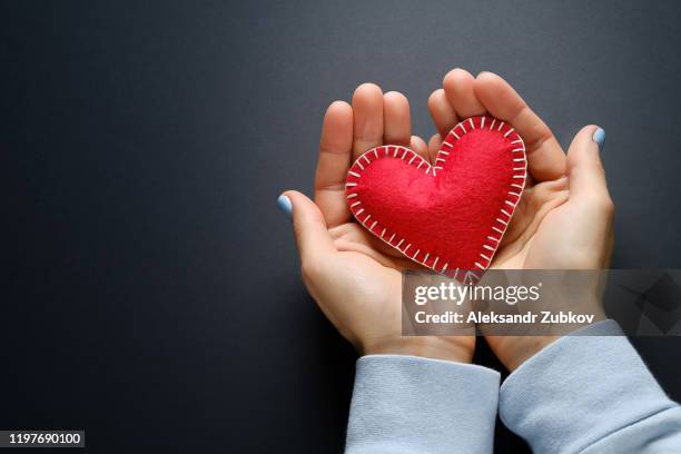 the girl is holding a red handmade heart on a black background. banner. - pendants stock pictures, royalty-free photos & images