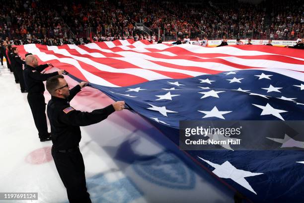 Members of the Glendale Police Honor Guard stretch a large American flag across the ice prior to the NHL hockey game between the Arizona Coyotes and...