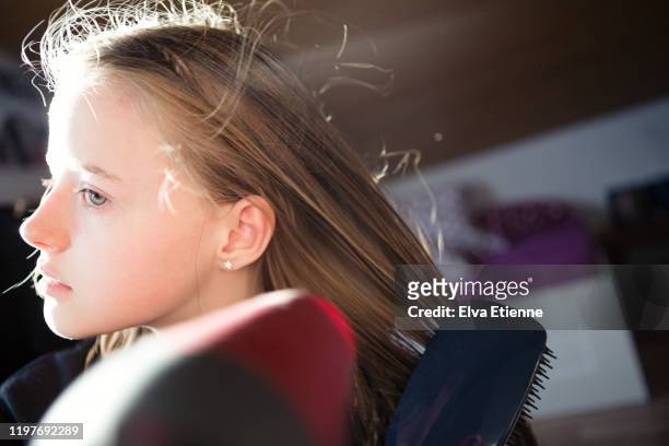 girl (12-13) blow drying her long hair with an electric hairdryer in a bedroom - boucle d'oreille photos et images de collection