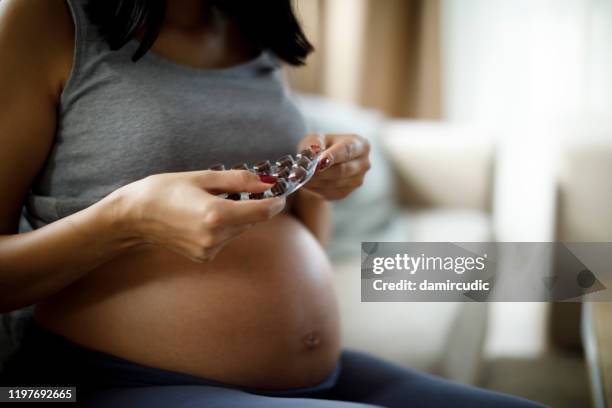schwangere frau, die pille zu hause - eisen stock-fotos und bilder