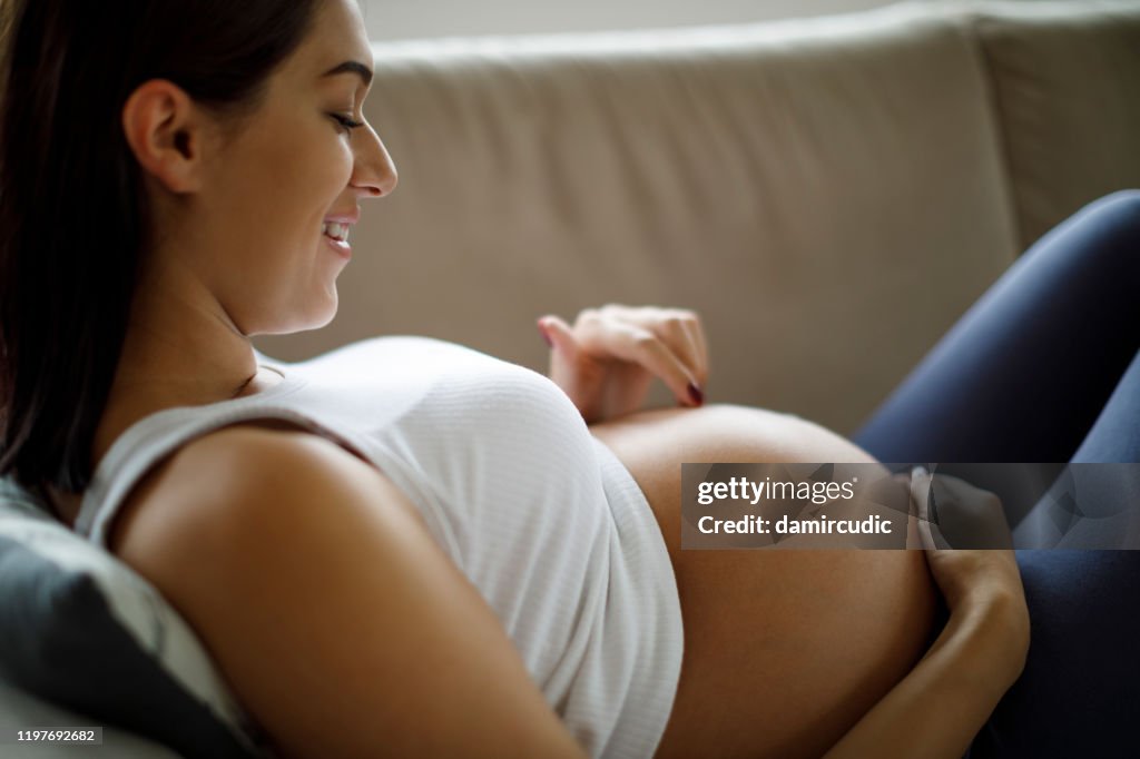 Pregnant woman playing with her belly at home