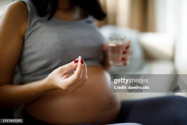 pregnant woman taking pill at home - eating human flesh stock pictures, royalty-free photos & images